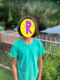 a young boy wearing a green shirt with a yellow r on it